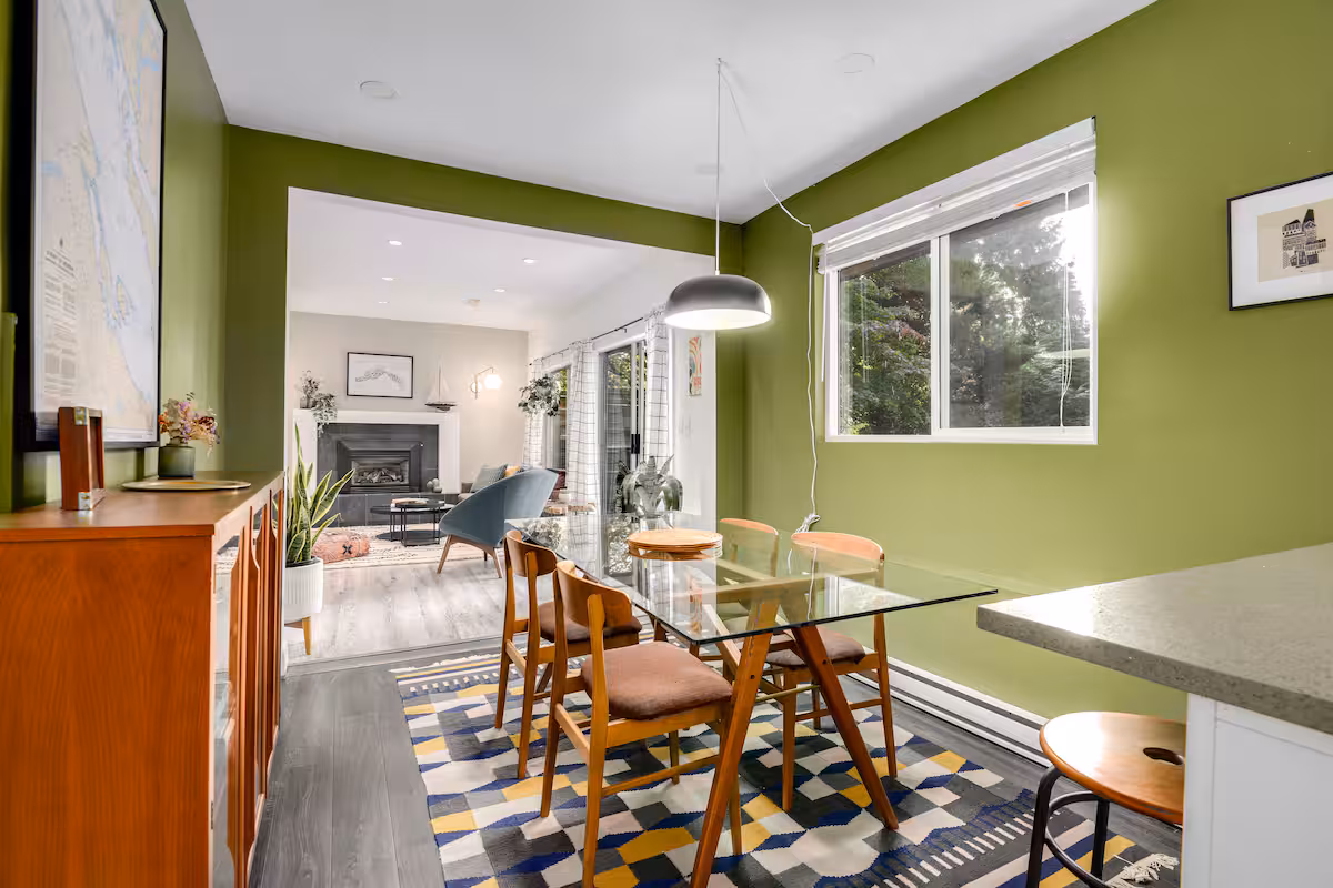 The dining table and kitchen, with green walls and a teak sideboard